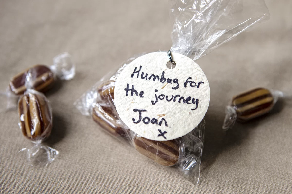 A bag of humbugs with a handwritten message reading 'humbug for the journey, Joan'