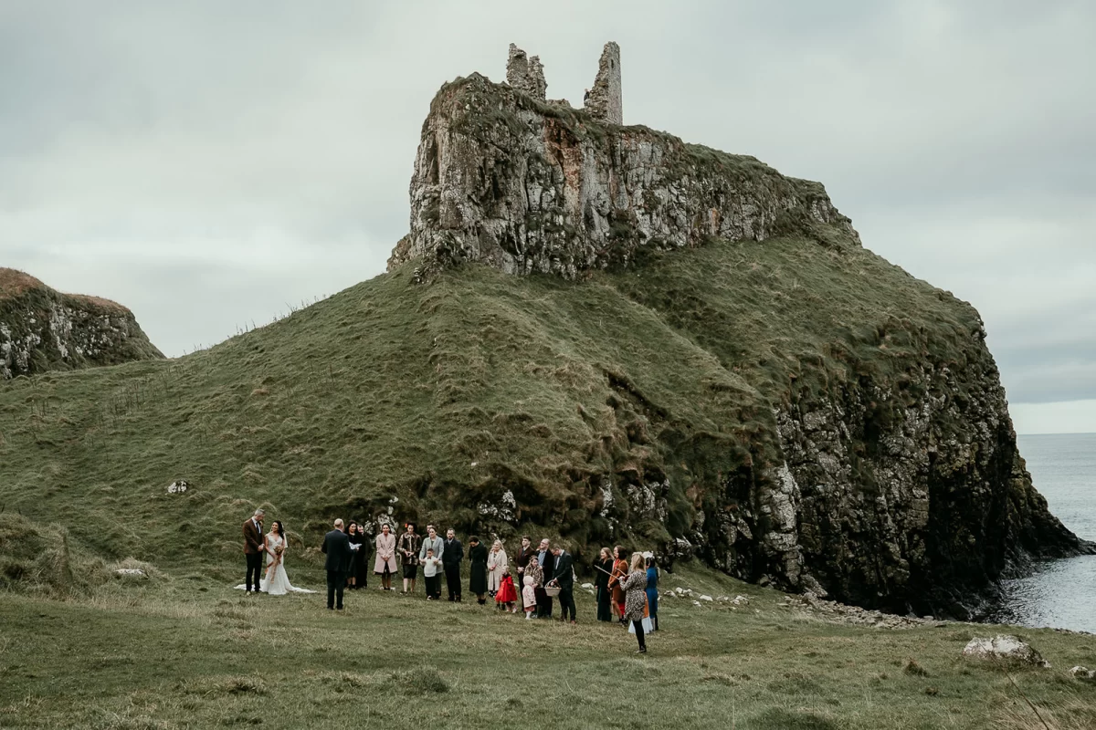 The wedding party seen from a distance, with the ruined castle above them on the cliff