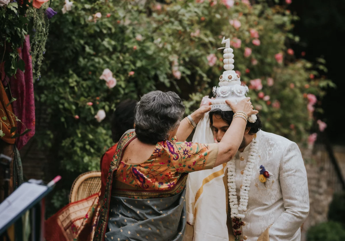 The groom's mother places a ceremonial Indian crown onto his head