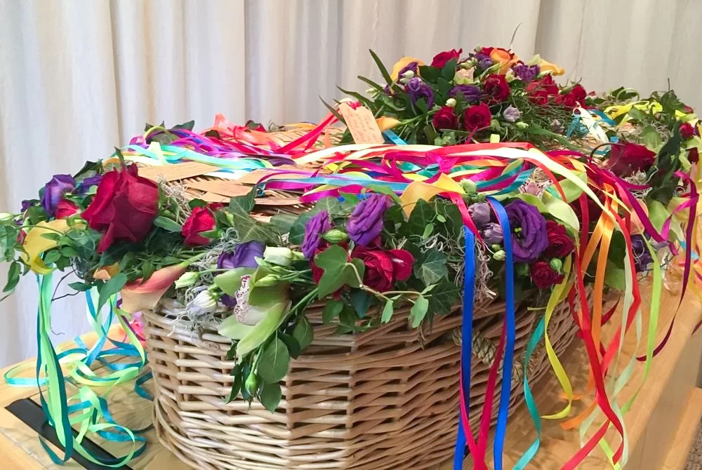 Bright and colourful ribbons decorate a wicker coffin