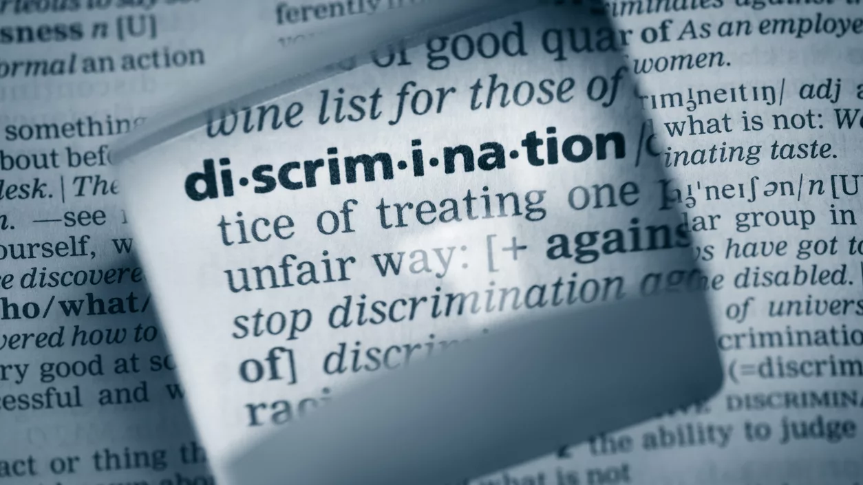 The Dictionary definition of the word “discrimination” photo taken through magnifying glass from a page of a dictionary with selective focus.