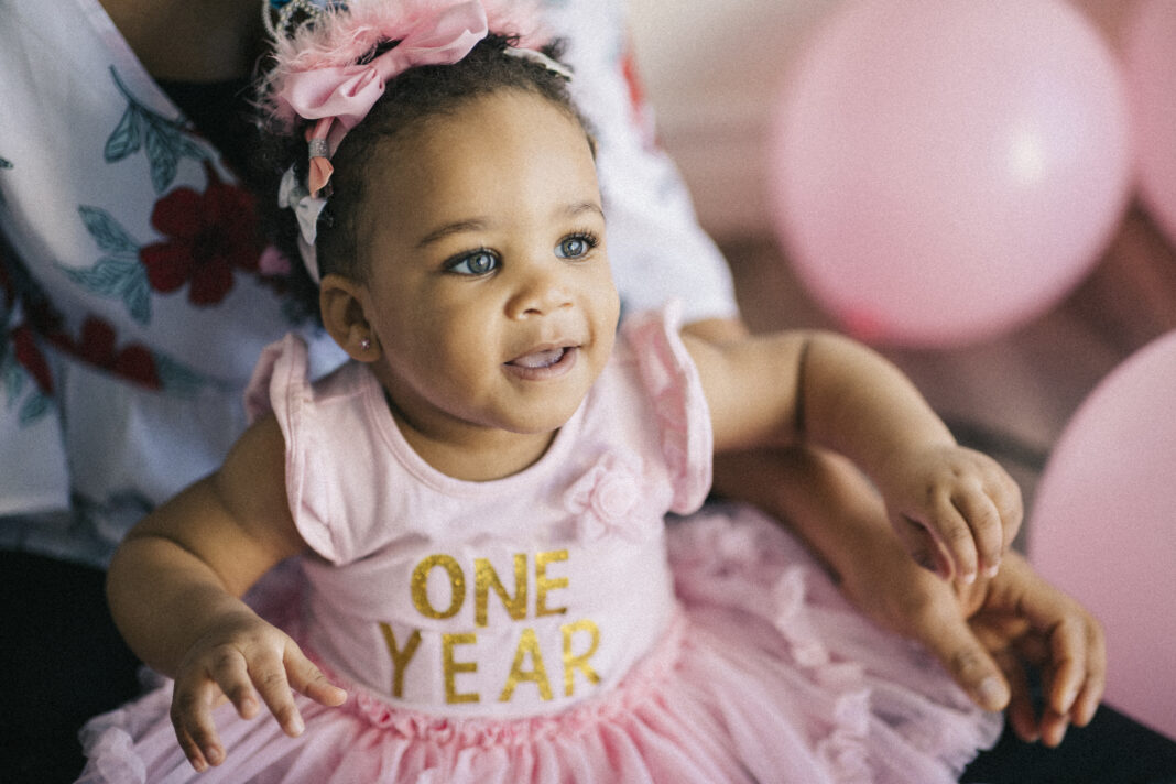 A beautiful one year old Black girl with a pink tutu and bow in her hair