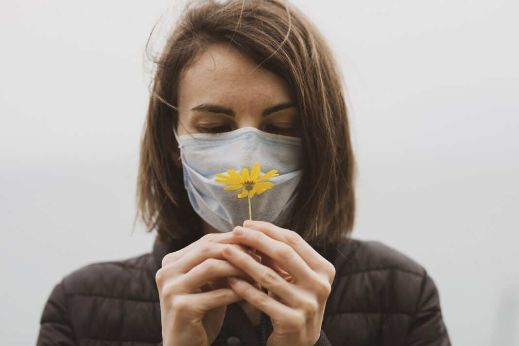 Female mourner wearing a face mask and holding a flower