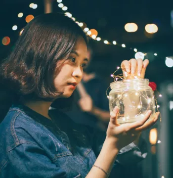 A woman putting fairy lights in a glass jar to save money on wedding decorations 